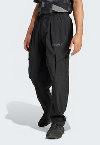 Juodos spalvos krovininės kelnės, laisvo silueto, su elastinga juosmens juosta ir keliais šoniniais kišenėmis. Ant šlaunies subtiliai matomas Terrex logotipas.