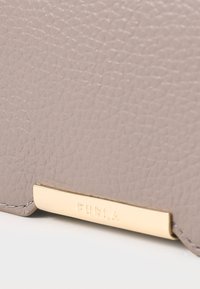 Light gray leather wallet with a textured surface. Features a gold-tone hardware accent with "FURLA" engraved. Edge stitching visible.