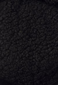 Black, textured fabric featuring a soft, plush surface with a wavy pattern. Material appears thick and cozy, ideal for warmth.