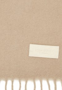 Beige uldhalstørklæde med en blød, tekstureret overflade og frynser i kanten. Har et rektangulært mærke prægret med "Marc O'Polo."