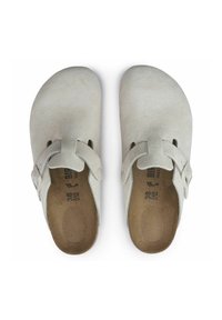 Zoccoli in suede grigio chiaro con design a punta arrotondata, strap regolabile e soletta beige. Texture morbida e profilo minimalista. Misura 38.