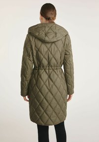 Oliwkowy pikowany płaszcz z kapturem, z paskiem w talii i wzorem w diamenty. Posiada długie rękawy i sięga do połowy uda.