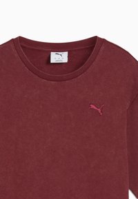 Bordo pamučna majica s okruglim izrezom, s malim ružičastim izvezenim Puma logotipom na lijevoj strani prsa. Mekana textura i ležeran dizajn.
