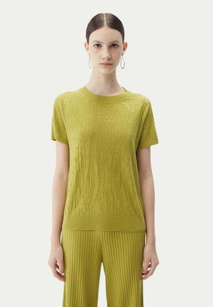 Grüner gestrickter Kurzarm-Top mit strukturiertem Muster und geripptem Ausschnitt. Kombiniert mit passenden gerippten Hosen.