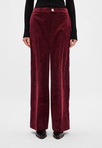 Vīna sarkanā plašo kāju bikses no mīksta korduroja auduma, ar priekšējo pogu aizdari un divām sānu kabatām.