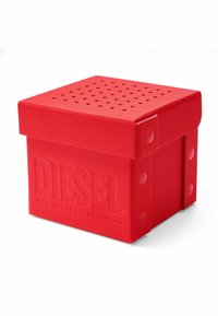 Boîte de rangement en forme de cube rouge, fabriquée en plastique texturé. Comprend un couvercle perforé et un logo "DIESEL" en relief avec des accents aux coins.