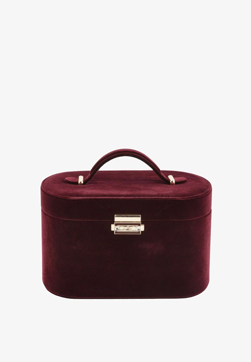 Bordowe welurowe pudełko o zaokrąglonym kształcie, z zapięciem z pozłacanego metalu i górnym uchwytem. Gładka faktura z lekko refleksyjną powierzchnią.