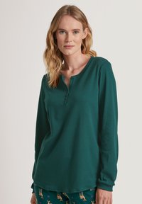 Langsleeve henley shirt in diep groen, gemaakt van zachte stof, met een knoopsluiting bij de halslijn en een relaxte pasvorm.
