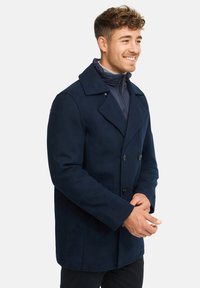 Marineblå uldblandings peacoat med dobbeltknaplukning, klapkraver og sidelommer, der har en struktureret overflade og sorte knapper.