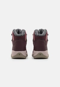 Fioletowo-różowe buty hikingowe z puszystym szarym kołnierzem, wzmocnionym piętą i teksturowaną podeszwą. Dwa oczka na sznurówki po każdej stronie.