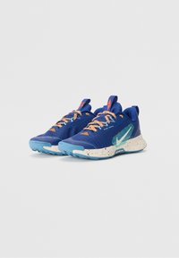 Baskets de sport bleues avec une tige en mesh texturé, lacets orange, accents turquoise et une semelle blanche marbrée.