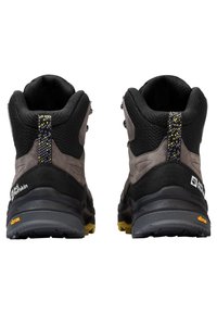 Scarponi da trekking a taglio medio con superiore in mesh nero e suede grigio, retro testurizzato, dettagli riflettenti e suola Vibram gialla e grigia.