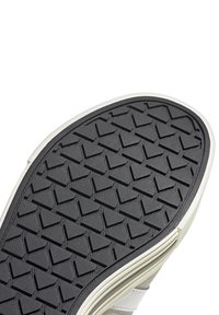 Semelle de chaussure en caoutchouc noir avec un motif de bande de roulement triangulaire et des bords blancs. Texture lisse avec une légère usure visible à la surface.