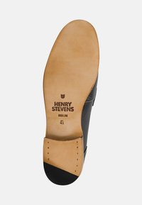 Sole di scarpa nera in pelle con imbottitura beige. Presenta il marchio impresso "HENRY STEVENS BERLIN" e la misura "4½" in nero. Superficie piatta e liscia.