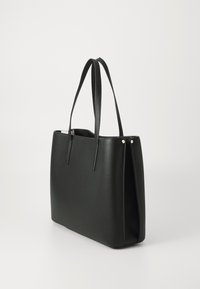 Sac fourre-tout en cuir noir avec deux longues poignées, forme rectangulaire, surface texturée, design minimaliste et accents en matériel doré.