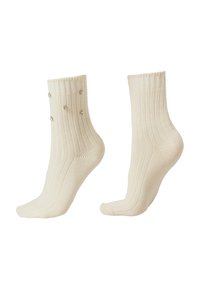Chaussettes aux chevilles côtelées de couleur crème avec des accents décoratifs en gemmes transparentes sur un côté, fabriquées à partir d'un tissu doux et extensible.