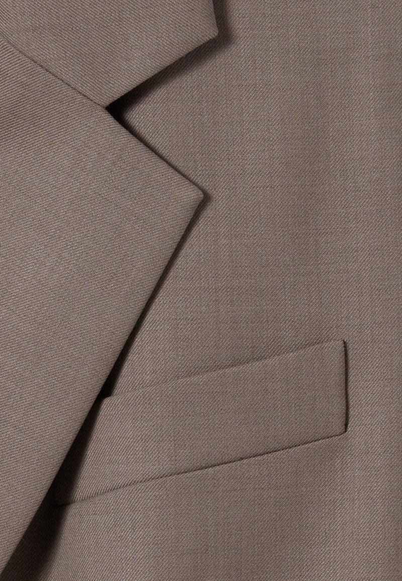 Brązowy żakiet z teksturowanej tkaniny, wyposażony w ostre klapy i małą, prostą kieszonkę po lewej stronie.