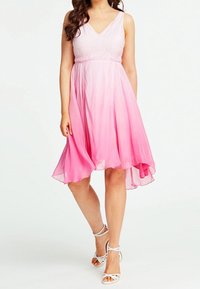 Vaaleanpunainen ombre-mekko, jossa on V-pääntie ja tiukka yläosa. Kaukana oleva, polveen asti ulottuva hame; läpikuultavaa kangasta, jolla on pehmeä tekstuuri. Yhdistetty valkoisiin remmisandaaleihin.