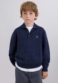 Granatowy sweter polo z dzianiny z kołnierzykiem, dwoma guzikami i przednią kieszenią; posiada turkusowe logo czaszki i skrzyżowanych kości na piersi.