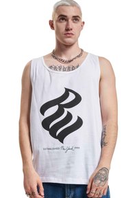 Top din bumbac alb, cu un design grafic îndrăzneț de culoare neagră și textul "ESTABLISHED New York 1999" în partea de jos. Colier din lanț argintiu vizibil.