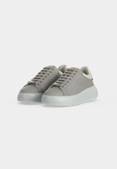 Ζευγάρι γκρι sneakers χαμηλού ύψους με χονδρές διαφανείς σόλες και γκρι κορδόνια που ταιριάζουν σε λευκό φόντο.