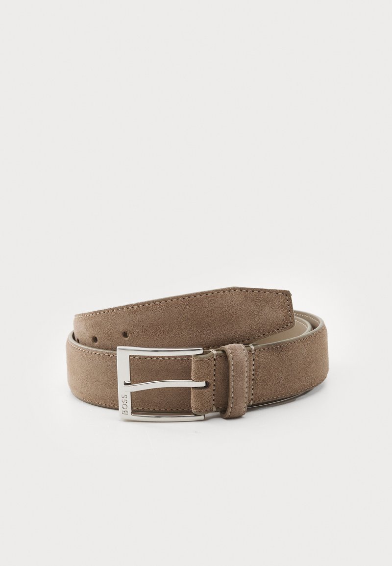 Curea din suede de culoare maro deschis cu o textură fină și cataramă din metal argintiu. Are cinci găuri și margini cusute pentru durabilitate.