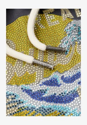 Sudadera con un diseño texturizado que presenta cristales plateados, dorados y azules, cordones blancos con puntas plateadas y un patrón gráfico de olas.