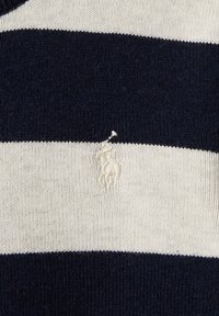 Marinblå och gräddstrimmig stickad tröja med ett litet trasigt område som avslöjar den underliggande tygtexturen. Material av bomullsblandning.