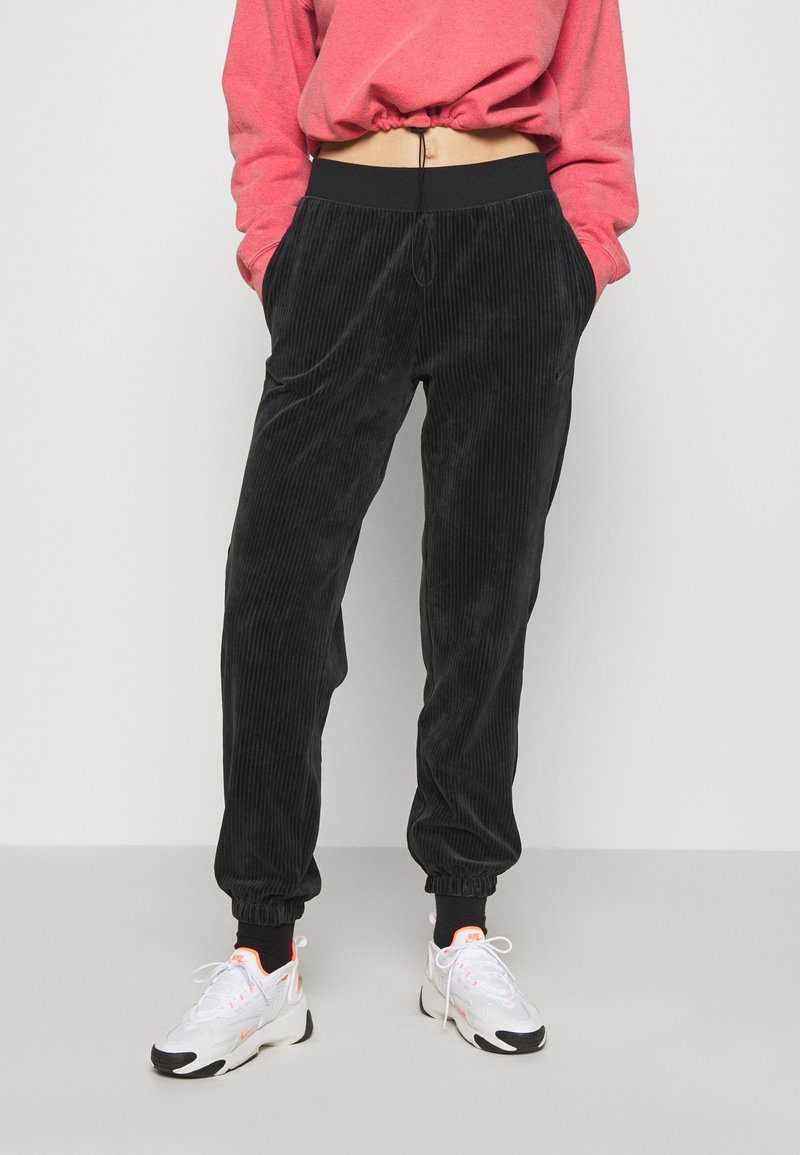 Svarta kordflöjtsbyxor med avslappnad passform, elastisk midja och dragsko. Tyget har en vertikalt ribbad textur.
