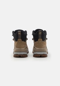 Bruine en zwarte wandelschoenen met suède en mesh bovenwerk, versterkte oogjes en rubberen zolen met een getextureerd loopvlakpatroon.