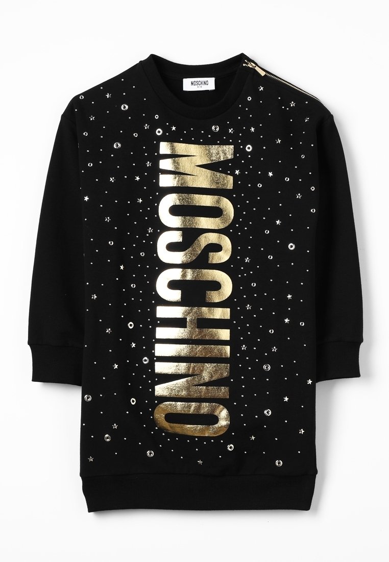 Robe noire à manches longues avec texte vertical doré "MOSCHINO", petits clous métalliques, motifs d'étoiles et de cercles, et détail zip à l'épaule.