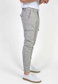 Lichtgrijze cargobroek van katoenmix, voorzien van meerdere zijzakken en een aansluitend ontwerp, gecombineerd met witte sneakers.