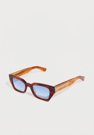 Lunettes de soleil rectangulaires écaille de tortue avec des branches ambrées et des verres dégradés bleus, présentées sur un fond blanc.