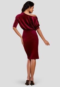 Robe bordeaux à épaules dénudées avec manches froncées, coupe ajustée et ourlet au genou. Confectionnée dans un tissu doux et scintillant.