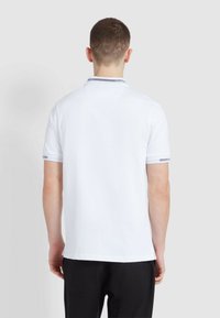 Polo shirt bianco con maniche corte, colletto a righe in contrasto e orlo dritto. Tessuto liscio, design minimalista.