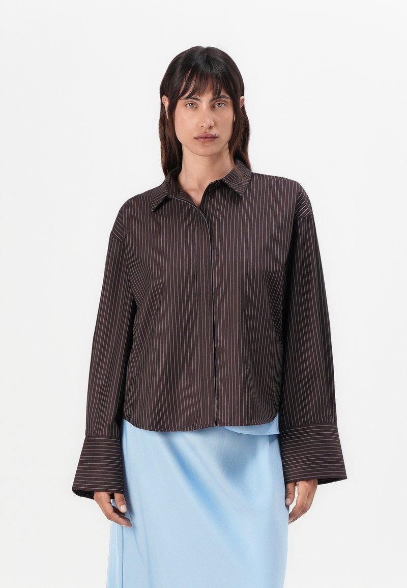 Chemise rayée marron à longues manches évasées, dotée d'un col et d'une fermeture à boutons sur le devant. Fabriquée en tissu lisse avec une coupe décontractée.