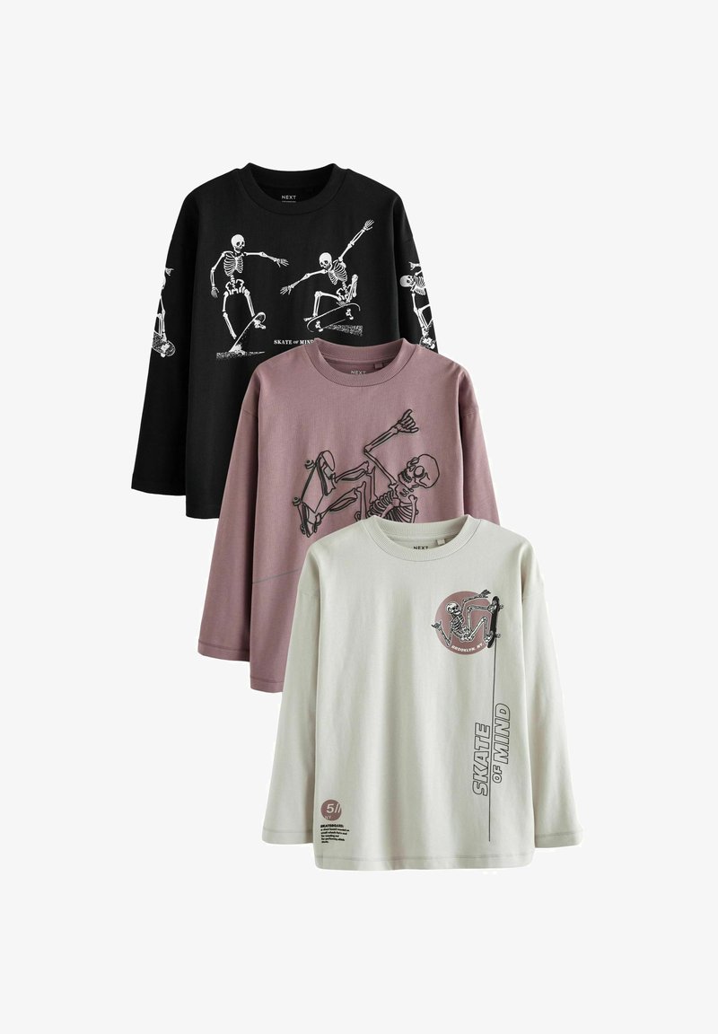Trzy t-shirty z długim rękawem: czarny z grafiką szkieletu, mauve z czaszką na desce skateboardowej oraz kremowy z okrągłym wzorem szkieletu i tekstem.