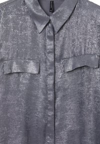 Silber-graues, strukturiertes Hemd mit Kragen, zwei Brusttaschen und vorderer Knopfleiste. Glattes Material mit leichtem Glanz. Größe XXL.