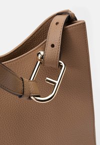 Sac à main en cuir marron avec une finition texturée. Comprend un détail en métal doré et une bandoulière réglable pour le transport.