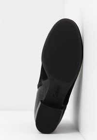 Bottine noire à semelle en caoutchouc texturée et talon bloc, affichant le nom de la marque "Gabor" et la taille sur la semelle.