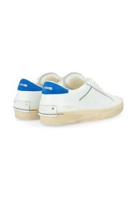 Sneakers bianchi low-top con accenti blu, design curvo, tomaia in pelle liscia, dettagli cuciti e suola in gomma beige testurizzata.