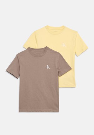 Két rövid ujjú, kerek nyakú póló, az egyik tégla barna, a másik pasztell sárga, mindkettőn kis fehér "cK" logó található a bal mellrészen.