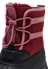 Rode waterdichte laars met een textiel bovenwerk met roze accenten, verstelbare veters en een zwarte rubberen zool voor grip.