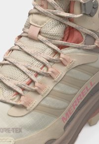 Μποτάκι πεζοπορίας Merrell ψηλό σε μπεζ και ροζ με πάνελ από δίχτυ, κορδόνια με σχέδιο και ετικέτα GORE-TEX αδιάβροχο εμφανής στην περιοχή των δακτύλων.