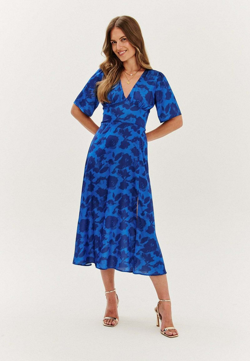 Modré šaty s květinovým vzorem, s výstřihem do V, krátkými rukávy a volánkovou sukní. Vyrobeno z lehkého materiálu, délka sukně je do poloviny lýtek.