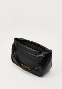 Svart läderhandväska med texturerad yta, utrustad med flätad handtag och logotypaccent i guldton. Dragkedja på toppen och rymligt innervägg.