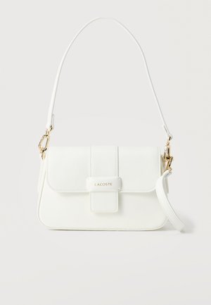 Λευκή δερμάτινη τσάντα ώμου Lacoste με κλείσιμο με καπάκι, εξαρτήματα σε χρυσό χρώμα και αποσπώμενο λουράκι σε μονόχρωμο φόντο.