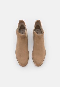 Bottines en suède tan avec des panneaux latéraux élastiques, bout pointu et couture décorative le long de la semelle. Taille 37 indiquée sur la semelle intérieure.