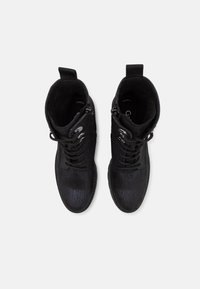 Bottes noires à la cheville en tissu texturé, avec un design à lacets, des accents en métal visibles et un bout lisse et arrondi.