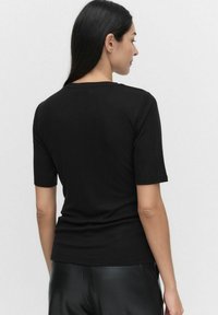 Zwarte t-shirt met korte mouwen, gemaakt van zachte stof, met een klassieke ronde halslijn en een aansluitende silhoutte. Achteraanzicht weergegeven.